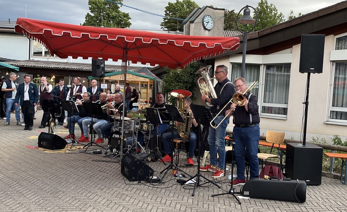 blech'n'takt live auf einem Marktplatz unter rotem Sonnensegel, das Publikum klatscht.