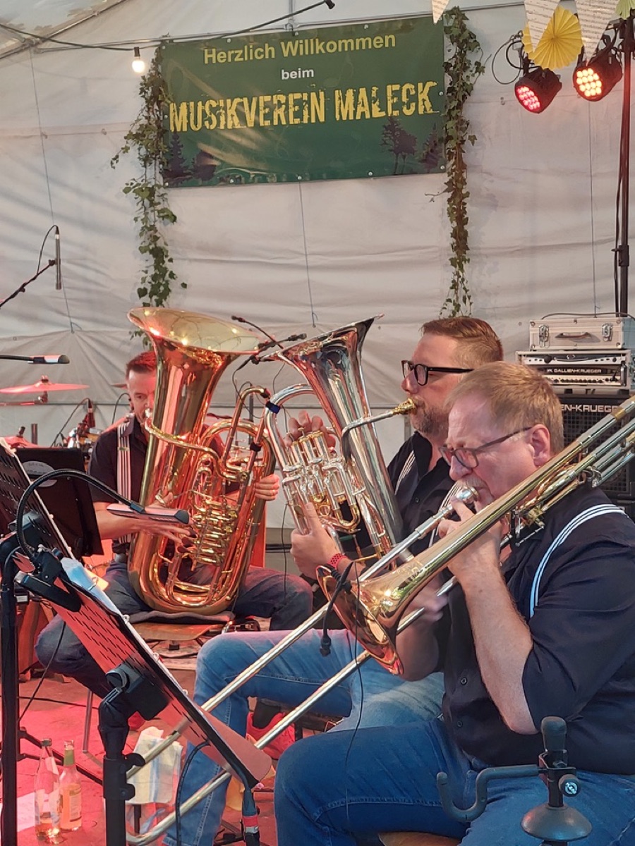 Detail-Aufnahme von Tuba, Euphonium und Posaune in goldenem Bühnenlicht beim Musikverein Maleck.