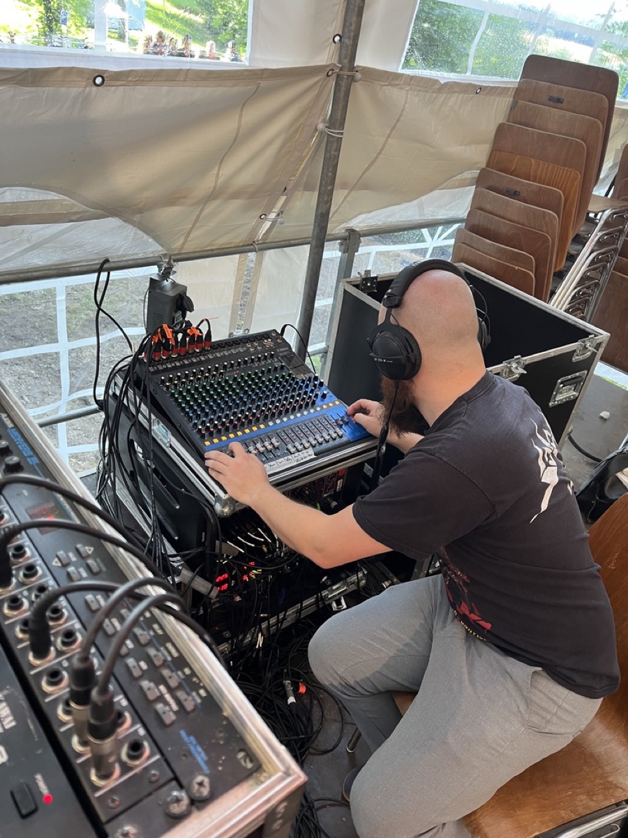 Unser Tontechniker am Mischpult mit Kopfhörern, konzentriert beim Mischen während eines Open-Air-Auftritts.