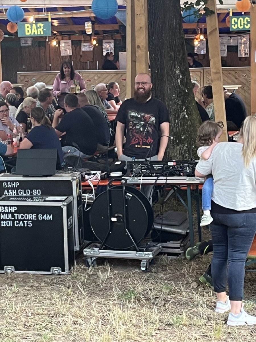 Unser Tontechniker während eines Auftritts vor Festzelt-Publikum, Bierbänke im Hintergrund.
